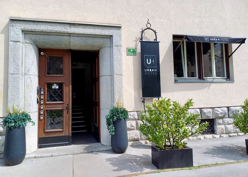 A stucco building has a black sign that reads, "Urban Hotel."