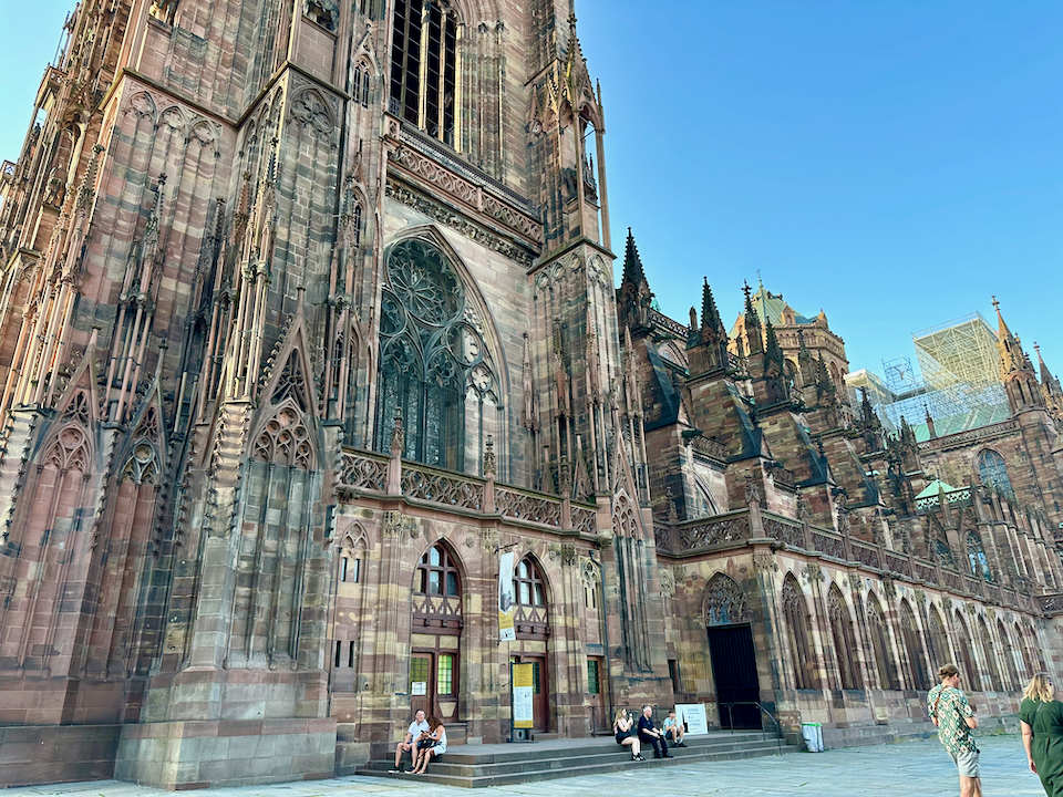 People lounge on the front steps of the Notre-Dame cathedral in Strasbourg, France