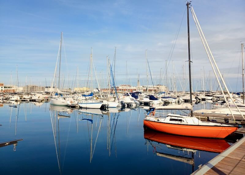 An orange boat sits in a full marina.