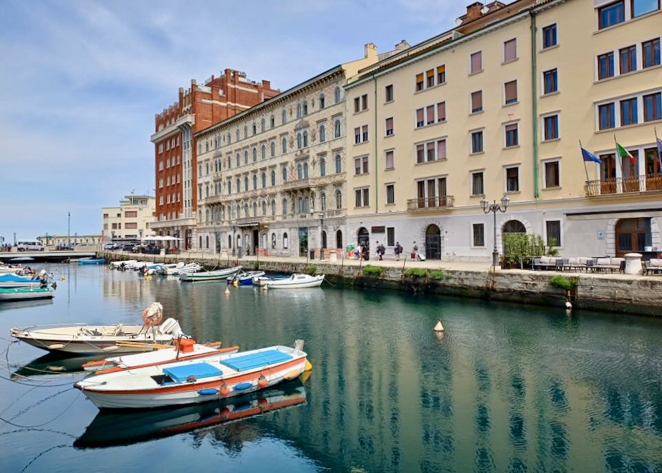 Small fishing boats sit tied to a cement canal.