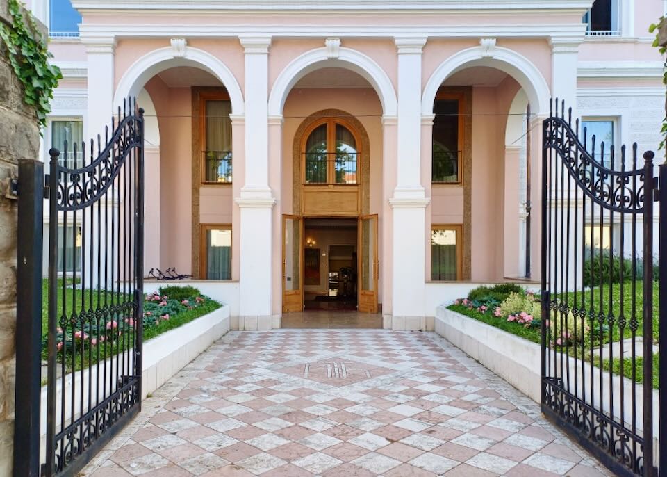 White arches stand out against the peach colored exterior walls of a hotels.