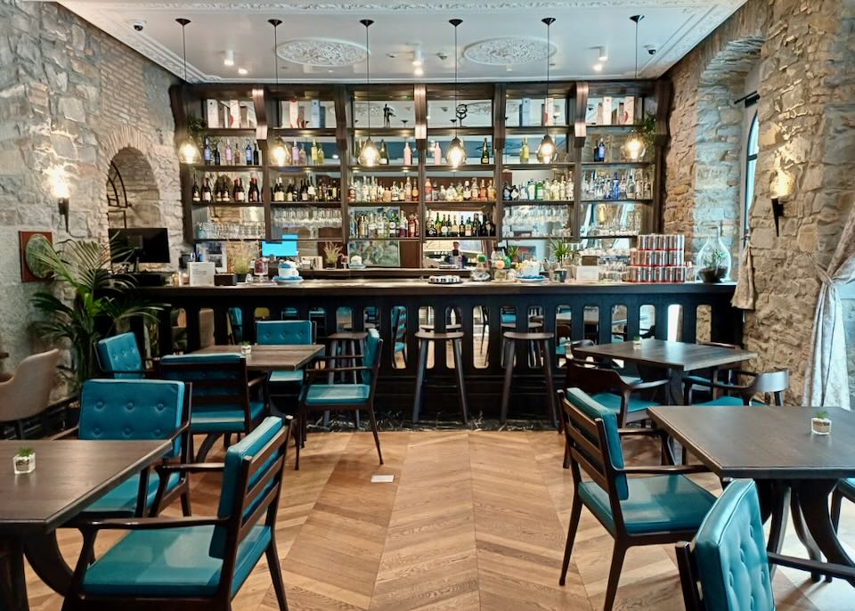 blue leather chairs sit in a wood and stone bar.