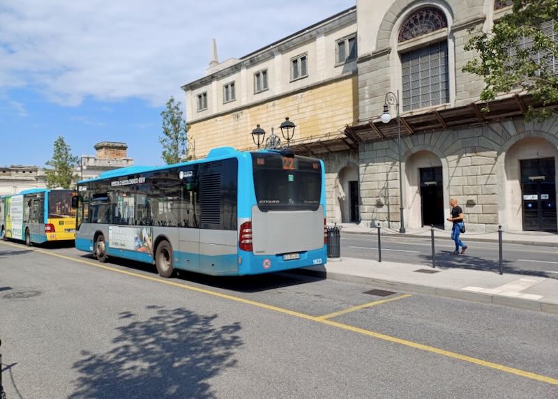 A blue bus pulls away from a station.