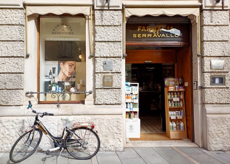 A bike sits parked outside a pharmacy.