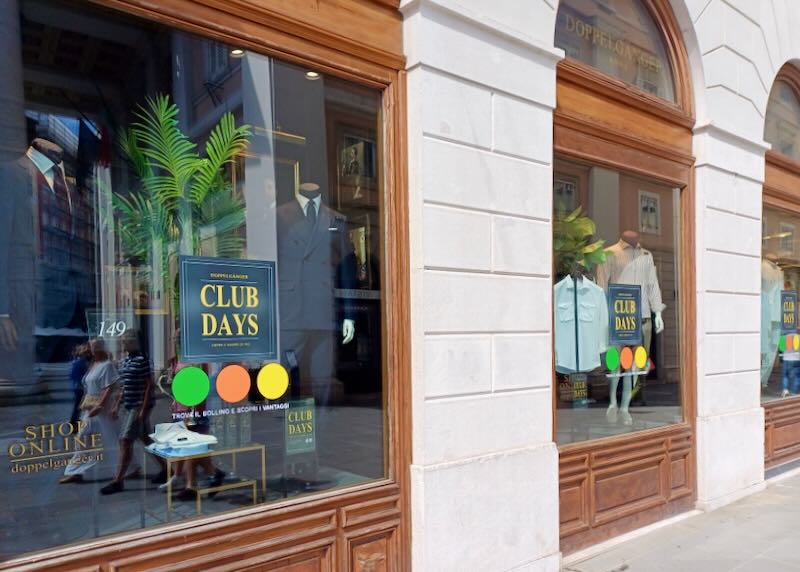 A clothing shop storefront with mannequins wearing suits.