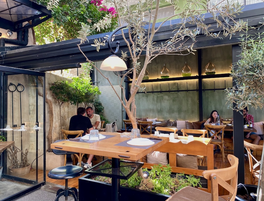 Outdoor dining area with olive trees at Peskesi restaurant in Heraklio, Crete.