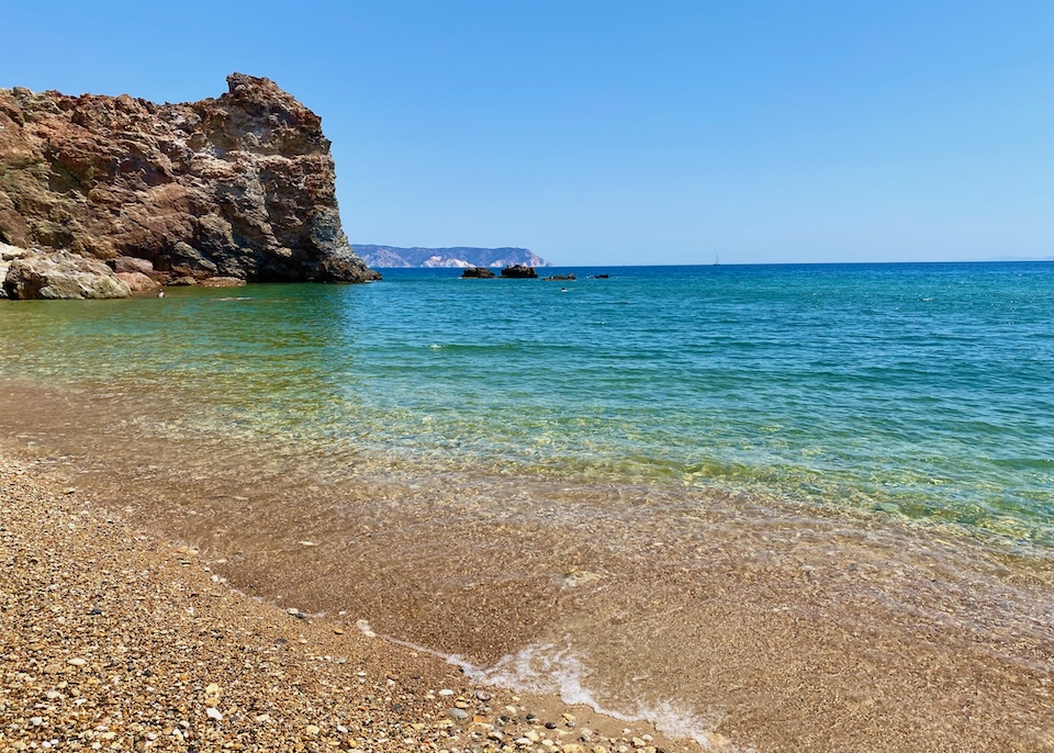 A sandy, pebbly beach with clear water and no waves at Thiorochio in Milos.